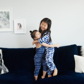 Two young girls hugging while standing on a couch.